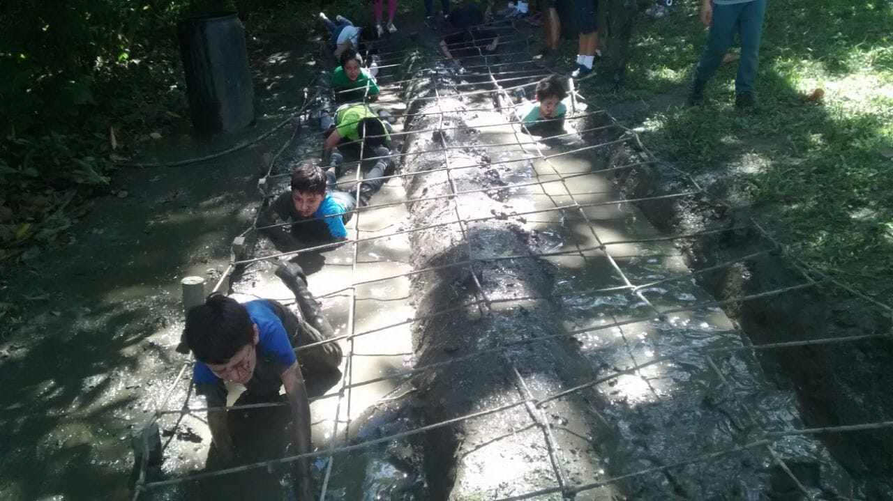 Convivencias en Nimaima con estudiantes con Awalí School trabajando de manera colaborativa para superar un reto de cuerdas bajas en Nimaima, enfocándose en la coordinación y el apoyo mutuo.