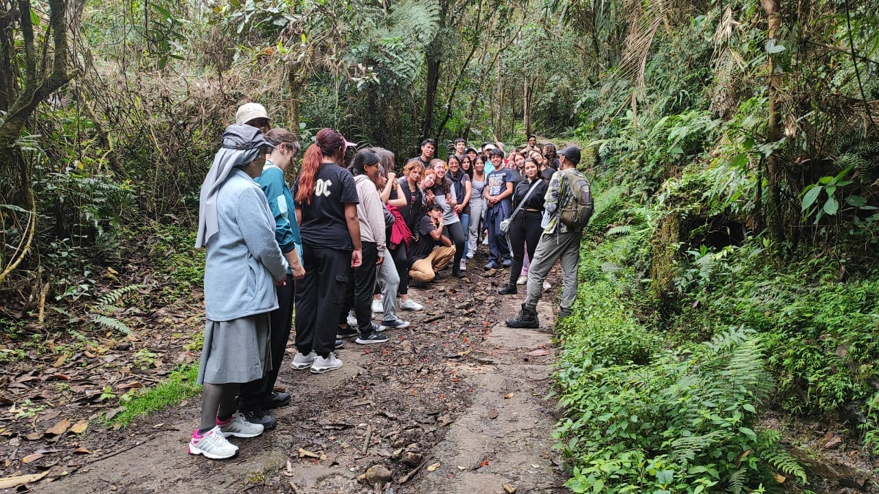 Estudiantes realizando registro en diario de campo y observación científica de flora nativa durante una expedición al Parque Chicaque.